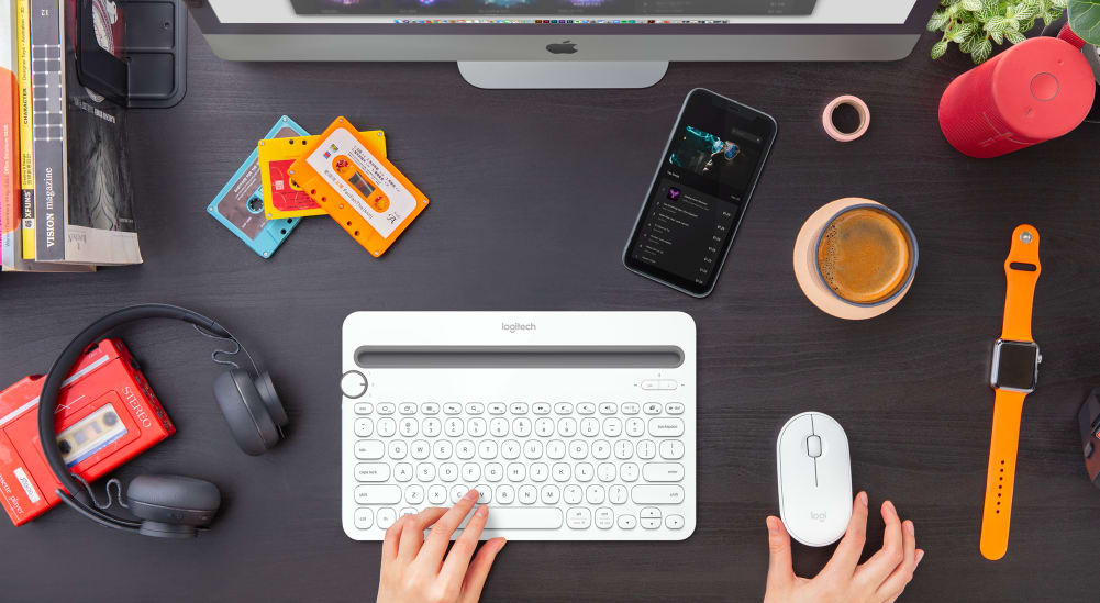 White keyboard and mouse on desk with apple computer and iPhone