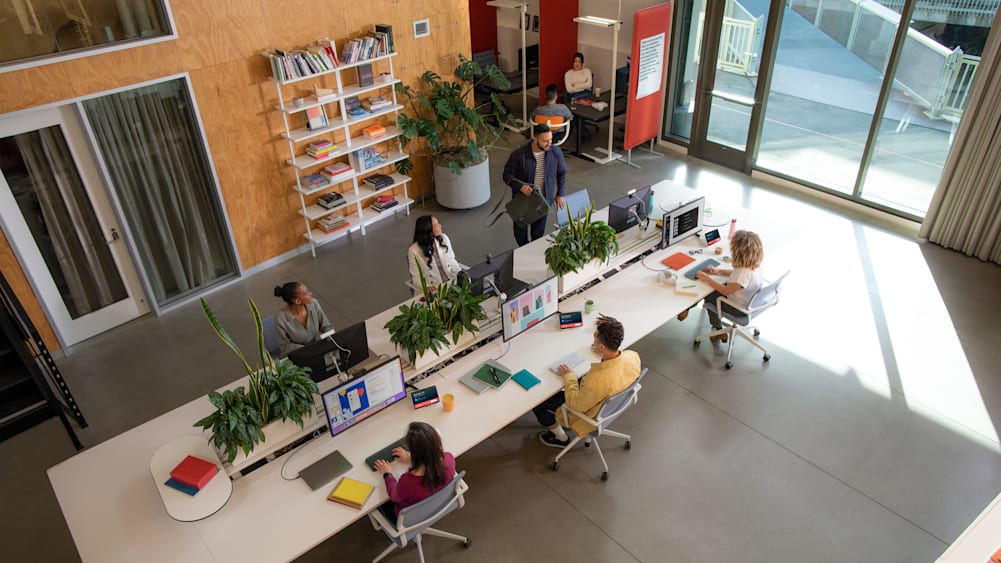 Overhead view of a bank of six occupied flex desks complete with monitors, peripherals, and a Logi Dock Flex.