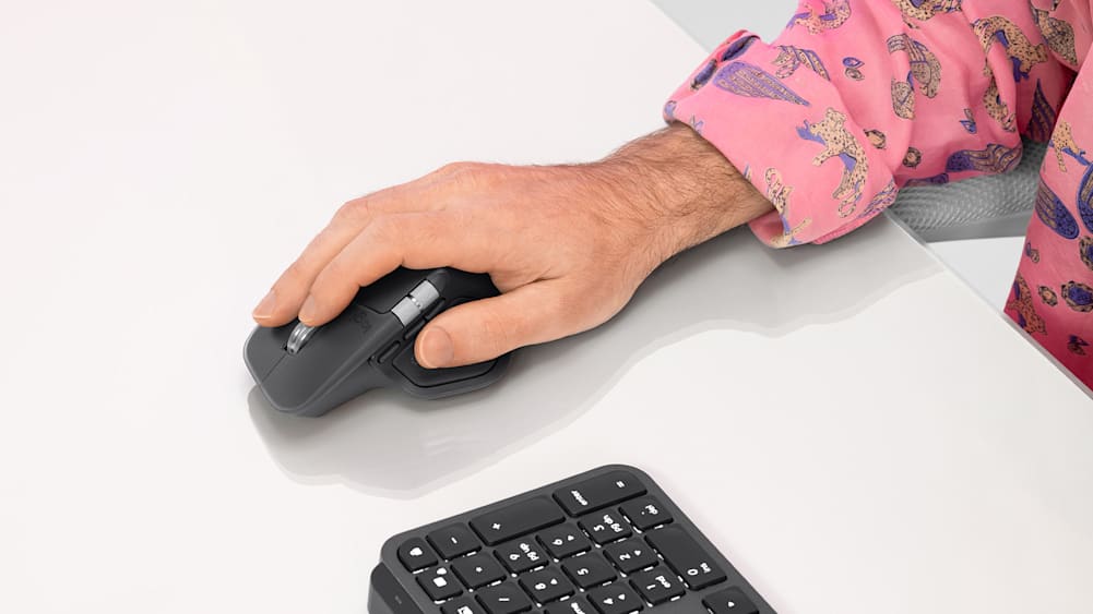 A man maneuvers the MX Master 4 for Business mouse in his right hand.
