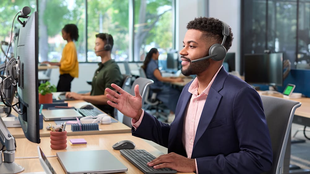 Man uses Zone Wireless 2 ES headset to communicate during virtual meeting at desk.