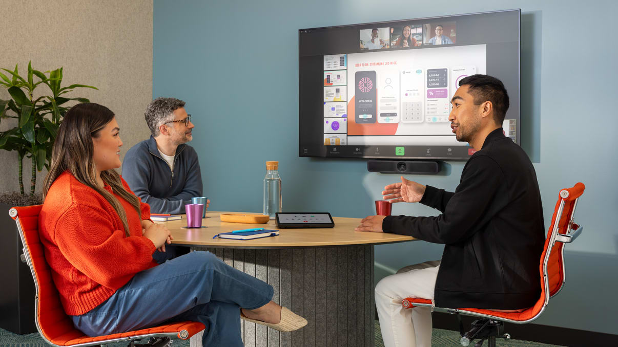 Employees in a small room conducting a hybrid meeting