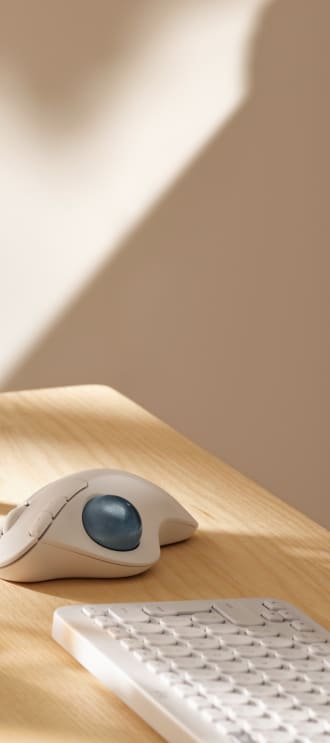 Λευκό ασύρματο ποντίκι trackball και πληκτρολόγιο επάνω σε γραφείο