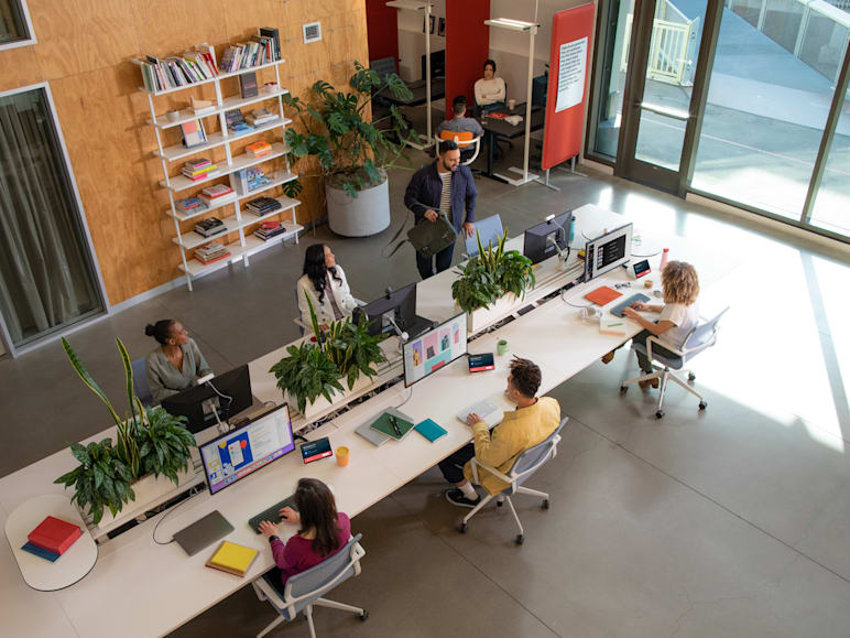 Overhead view of a bank of six occupied flex desks complete with monitors, peripherals, and a Logi Dock Flex.