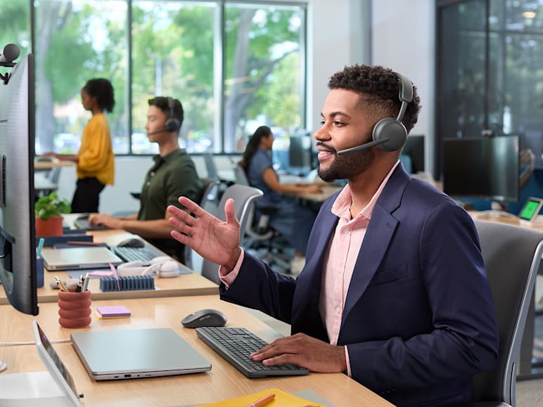 Man uses Zone Wireless 2 ES headset to communicate during virtual meeting at desk.