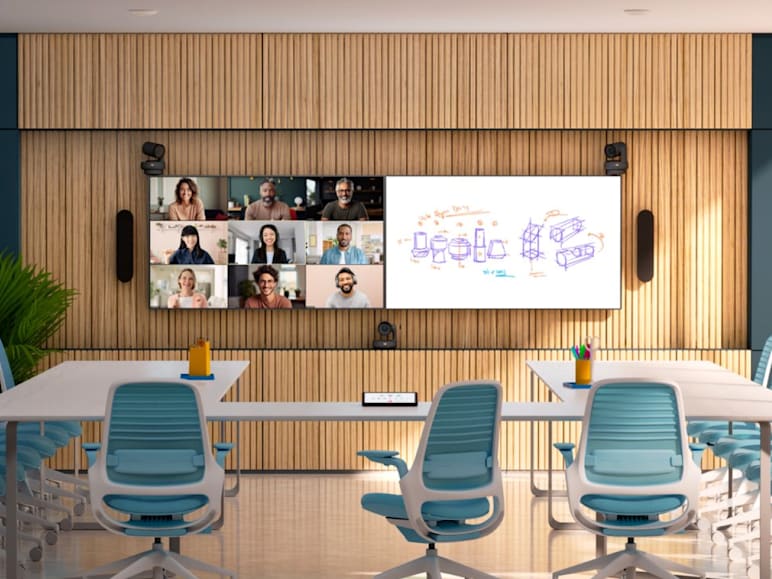A Logitech-equipped meeting room with a large screen displaying a video conference with multiple participants and a digital whiteboard