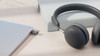 Headset placed on desk next to laptop with wireless receiver