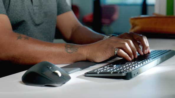 Visar en händer som skriver på ett tangentbord bredvid Logitech Business-möss